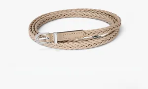 Détail d'une ceinture tressée kaki avec boucle ardillon argentée sur fond blanc