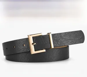 Detailed macro view of black leather belt strap with textured litchi pattern and gold buckle