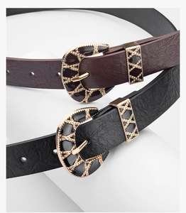 Close-up of Western vintage belts with engraved gold buckles and black enamel detail