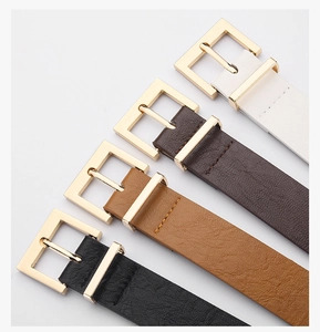 Close-up of four leather belts in white, brown, and black with gold square buckles
