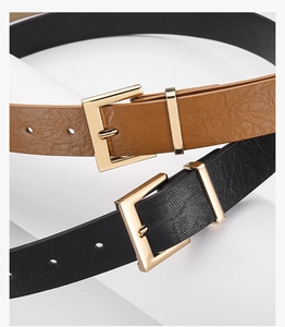 Detail view of brown and black leather belts with golden square buckles and textured finish