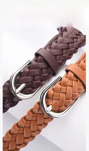 Detail of woven leather belts in dark brown and tan with silver metal buckles