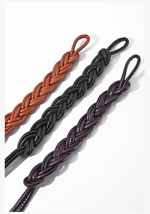 Close-up of woven leather belts in brown, black and dark purple with metallic loops