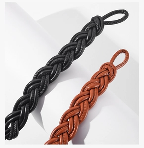 Close-up of woven leather belts in black and brown with detailed stitching and ring loops