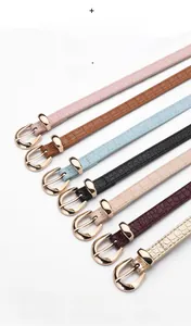 Détail de ceintures fines en cuir avec motif crocodile et boucles dorées en sept tons