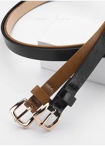 Detail of slim black and brown PU belts with gold pin buckles on white geometric stands