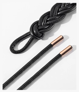 Close-up of black braided leather belt with luxury rose gold metal cylinder end caps