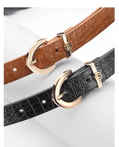 Detail of elegant gold alloy buckle on textured black and brown crocodile pattern leather belts