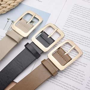 Three minimalist women's PU leather belts with polished gold square buckles in warm lighting