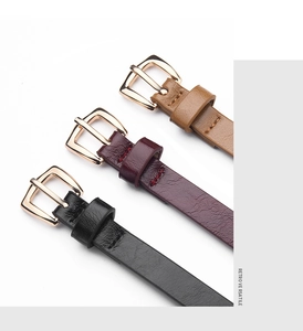 Close-up of slim PU leather belts in black, burgundy and brown with gold pin buckles