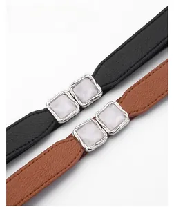Detail of slim elastic waist belts with alloy buckle and white moire inlay decoration