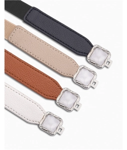 Detail of four elastic waist belts with textured leather ends and silver metal buckles