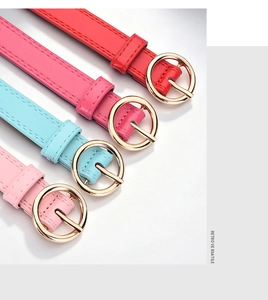 Detail of colorful PU leather belts with gold round buckles in red, pink, and blue
