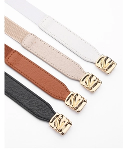 Detail of four thin elastic waist belts in black, brown, beige, and white with gold buckles