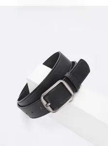 Detail of black leather belt featuring a matte silver buckle on a minimalist display