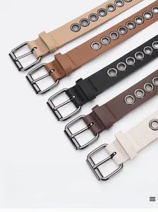 Macro view of multi-colored faux leather skinny belts with metal eyelets and silver buckles