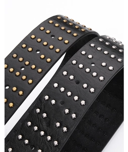 Detailed macro view of black punk leather belts featuring double-row metal studs and grommets