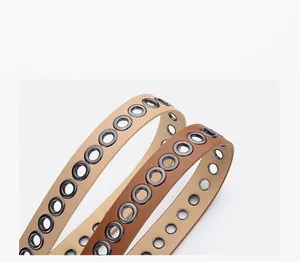 Close-up of thin PU leather belts with dense metal eyelets in khaki and brown