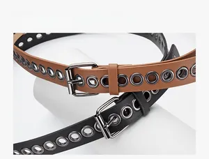 Detail view of leather belts showing metallic eyelets and matte square buckle design