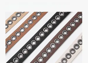 Close-up of four slim leather belts in beige brown and black with metallic eyelets detail