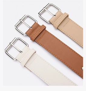 Detail of three leather belts in white, brown and beige with silver pin buckles