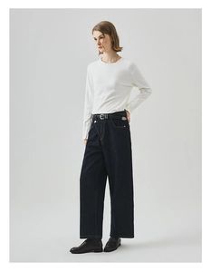 Detail der hoch taillierten, lockeren blauen Jeans mit weißem Langarmshirt mit Knopfleiste
