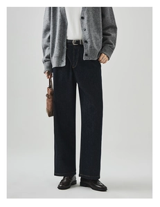 Dunkelblaue Jeans mit weitem Bein, kombiniert mit braunem Gürtel und grauer Strickjacke