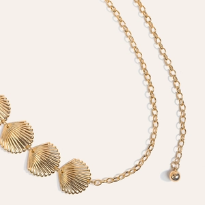 Détail de la chaîne de taille dorée avec breloques en forme de coquillage et pendentif