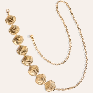 Détail d'une ceinture chaîne dorée en forme d'éventail avec fermoir et texture coquille