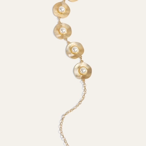 Detailed macro view of golden sunburst metal disks with embedded pearls on a belt accessory