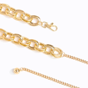 Detailed macro view of gold metal link waist chain with lobster clasp and ball pendant