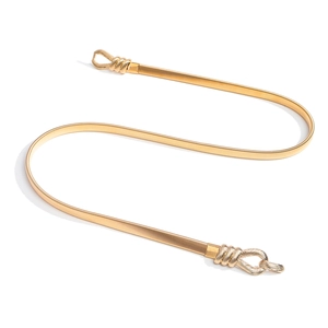 Détail d'une fine ceinture métallique dorée élastique avec chaîne serpent et boucle à nœud