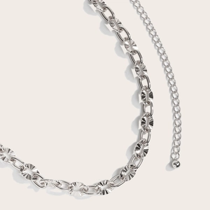 Close-up of hollowed metal waist chain featuring ornate carved links and a round ball pendant