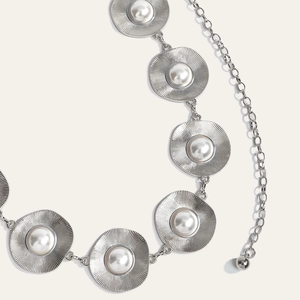 Detail of silver metal chain belt with pearl accents and sunburst texture finish