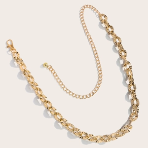 Detailed macro view of the golden metal waist chain with textured circular links and lobster clasp