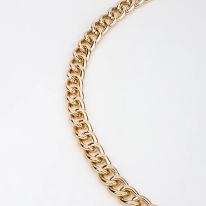 Detailed view of glossy gold chunky metal chain link with high-shine polished finish