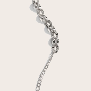 Close-up of silver metal chain waist belt featuring faceted oval links and extension chain