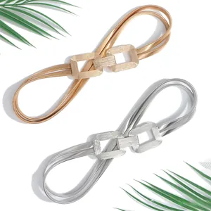 Close-up of golden and silver elastic waist belts with rectangular interlocking buckles