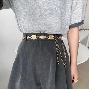 Detailed macro view of vintage gold waist chain with relief plates and hanging metal tassels