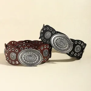Close-up of bohemian leather belts with floral engraved buckles and metal eyelets