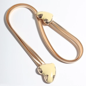 Detail of golden metal spring belt with beige enamel heart buckle and hammered metal edge