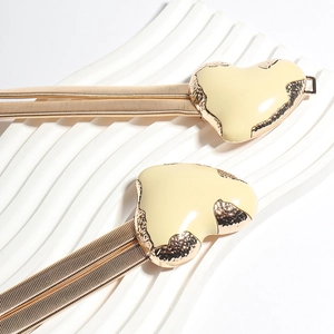 Detail of gold metal spring waist chain with a cream enamel heart-shaped buckle clasp