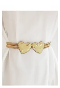 Close-up of heart-shaped buckle on gold elastic waist belt paired with a white dress