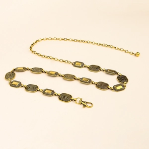 Detailed view of vintage gold metal waist chain with embossed links and ball pendant