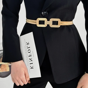 Close-up of golden elastic belt with dual square metal buckles on a black suit blazer