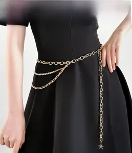 Detail einer mehrlagigen goldenen Metall-Taillenkette mit Strass und Sternanhänger auf Kleid