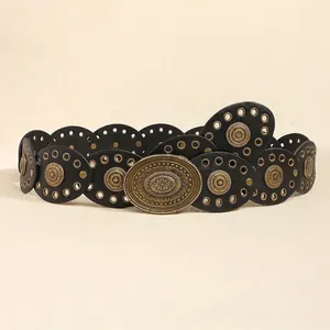 Detail of bohemian black leather belt with bronze sunburst carvings and metal grommets