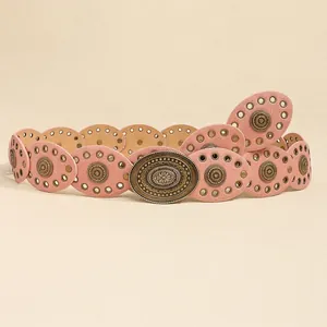 Macro detail of pink leather belt with metallic studs and engraved floral buckle