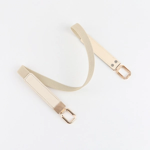 Detail of beige elastic waist belt with leather accents and gold-tone metal buckles