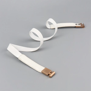 Detail of white elastic waist belt with elegant bronze metal buckles in S-curve shape